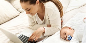 Mother searching for information online while baby sleeps